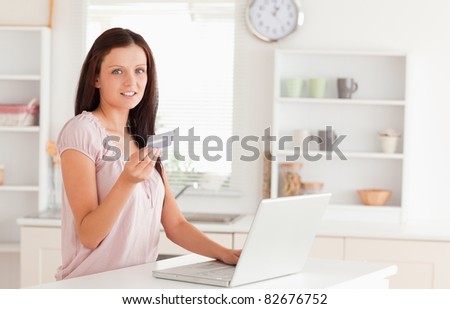 A woman is showing a credit card by laptop