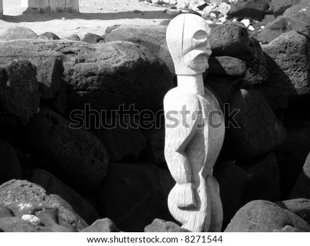 black and white picture of a Hawaiian Tiki idol tucked in to a bed of volcanic rock.