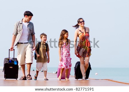A family of 4 arriving at the resort with their luggage. Royalty-Free Stock Photo #82771591