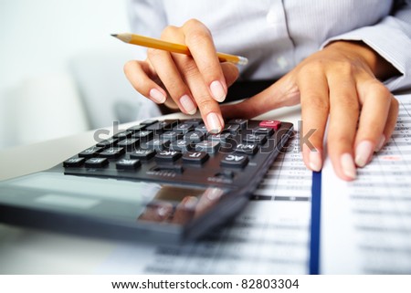 Photo of hands holding pencil and pressing calculator buttons over documents Royalty-Free Stock Photo #82803304