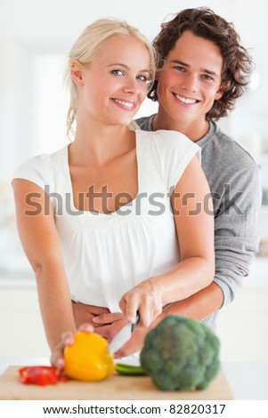 Portrait of a lovely couple slicing pepper in their kitchen