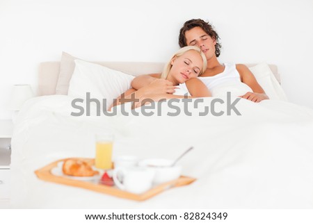 Sleeping couple with the breakfast put on a tray with the camera focus on the models