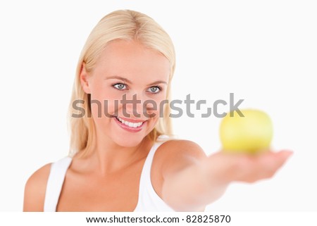 Blond woman holding an apple in a studio