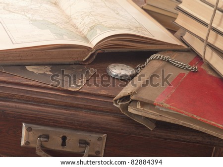 antique background with the old map and a clock on a wooden table