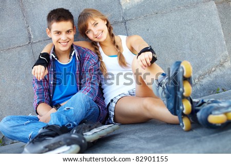Couple of happy teens on roller skates looking at camera