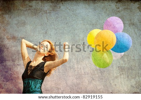 Redhead girl with colour balloons at blue sky background. Photo in old image color style.