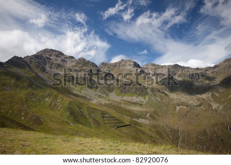 austrian alps with cloudy sky and green lawn