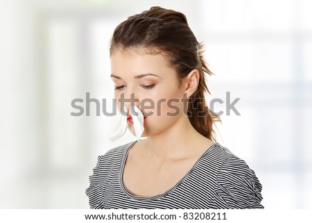 Teen woman with tissue in her nose, isolated on white background