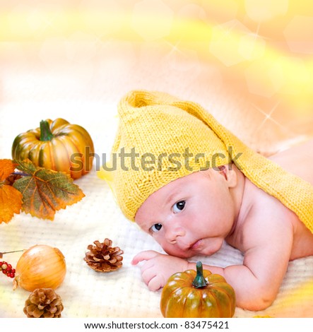Sweet newborn baby boy among autumn harvest