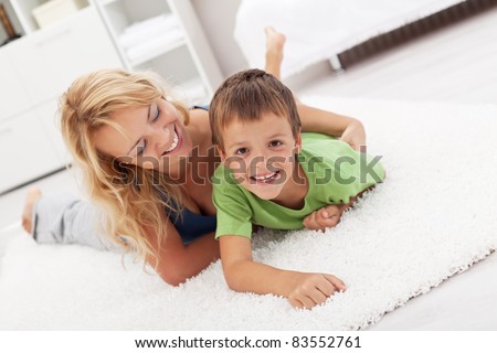 Happy mother and son playing in the living room wrestling on the floor