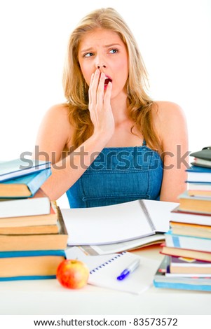 Shocked young girl sitting at desk with piles of books