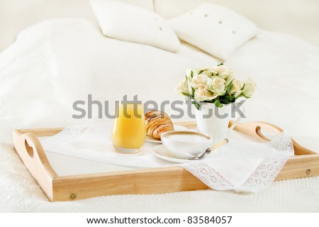 Breakfast in bed with coffee, orange juice and croissant on a tray