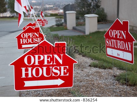 Red and white open house sign close-up with more signs in the background