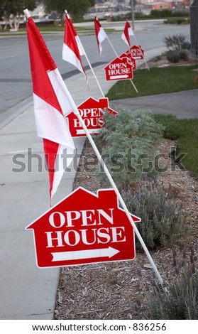 White and red open house signs with arrows and decorated with flags