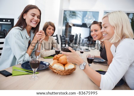 Women showing something to her friends on mobile phone at dining table - Shallow Depth of field critical focus on phone
