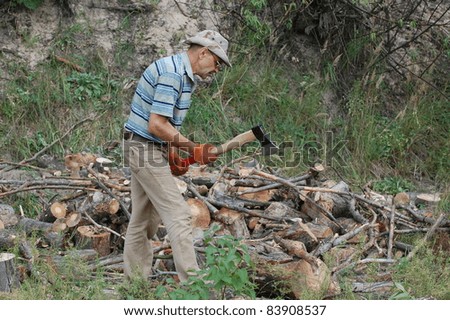 Man with axe chop logs for firewood.Ukraine
