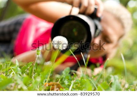 photographer, female  photograph with camera taking a macro  picture of flower