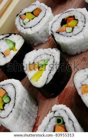 Maki Sushi and Nigiri - Maki Rolls and California rolls made of fresh raw Salmon, Tuna and Eel with Cream Cheese and Avocado . Isolated over white background . on wooden plate