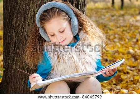 beautiful little girl draws outdoors