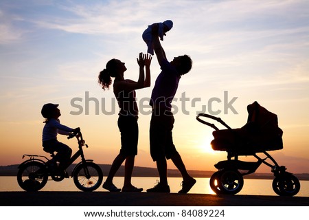 Silhouettes of happy parents having good time with their little children on the seacoast