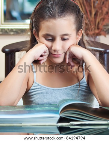 Beautiful small hispanic girl reading a book at home
