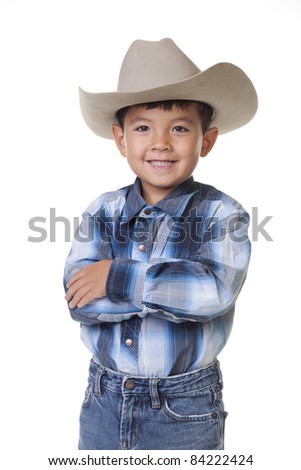 A young boy in cowboy clothes crosses his arms and shows a big smile. Royalty-Free Stock Photo #84222424