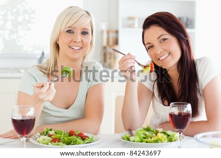 Cheerful young Women eating salad in a kitchen