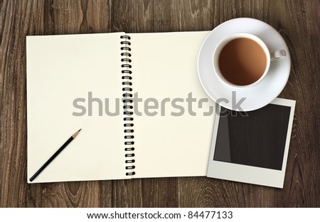 blank notebook with photo frame and coffee cup on wooden background