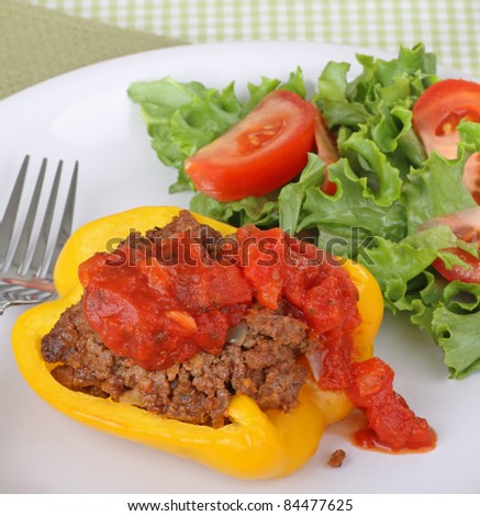 Stuffed yellow pepper with a salad on a plate