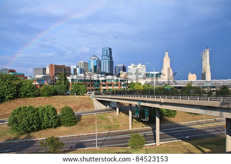 A cityscape view of the downtown Kansas City, Missouri area with a rainbow over the city.  Kansas City borders major rivers and is a major city in the Great Plains.