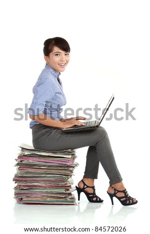 Attractive smiling young business woman using laptop sitting on her paperwork