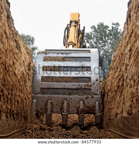Excavator digging a deep trench Royalty-Free Stock Photo #84577933