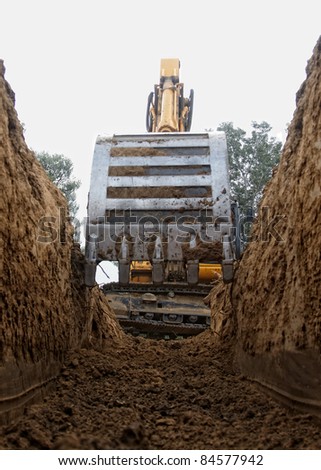 Excavator digging a deep trench Royalty-Free Stock Photo #84577942