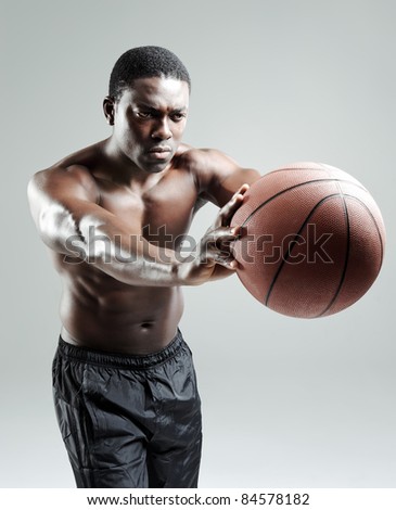 Shirtless muscular man passing a basketball in studio