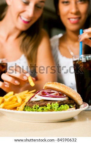 Fast food hamburger and fries in a restaurant on a dish - close-up and focus on the burger