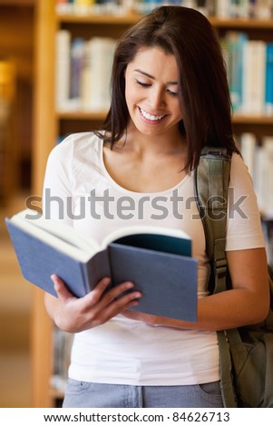 Portrait of a cute student reading a book in the library