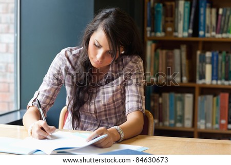 Young student writing in a library