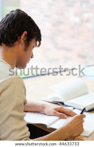 Portrait of a young student writing an essay in the library