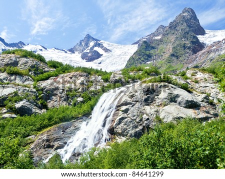 Huge waterfall among the rocky mountains covered with snow