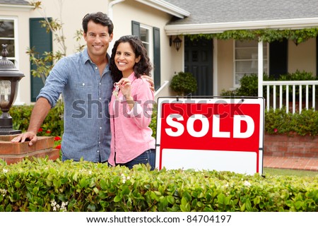 Hispanic couple outside home with sold sign Royalty-Free Stock Photo #84704197