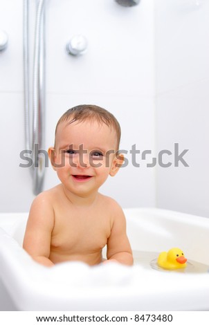 Portrait of a Baby smiling in the bathtub .