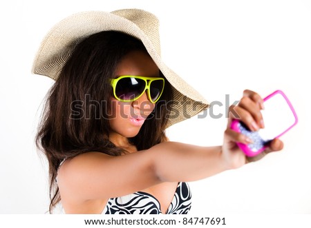 Beautiful young brunette woman in cowboy hat and sunglasses taking a photograph with a mobile cell phone - isolated on white