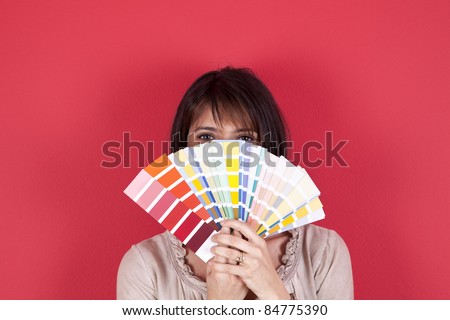 woman next to a red wall looking to a color paint palette (selective focus)