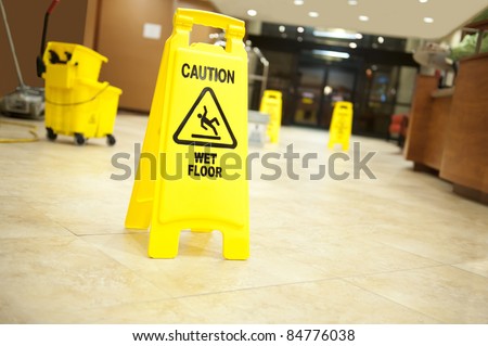 Lobby floor with mop bucket and "caution wet floor" signs, selective focus on nearest sign Royalty-Free Stock Photo #84776038