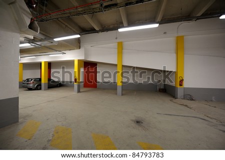 Parking garage, underground interior with a only one parked car.