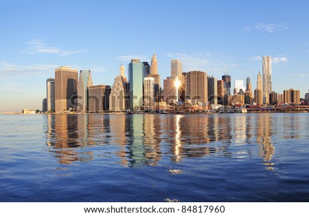 Lower Manhattan skyline panorama over East River with reflection and blue sky in New York City
