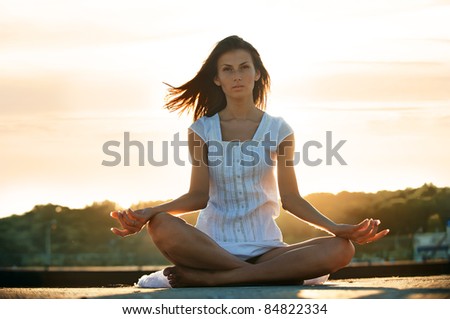 Young attractive woman doing yoga on sunset background