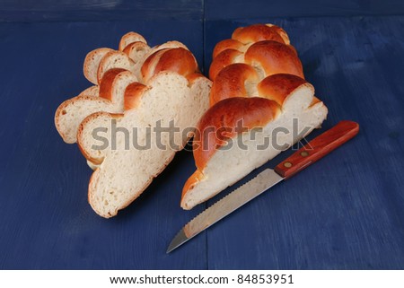 baked product : cutted golden challah on blue wooden table