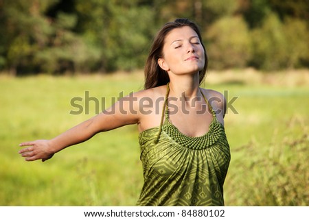 A picture of a young relaxed woman smiling over natural green background