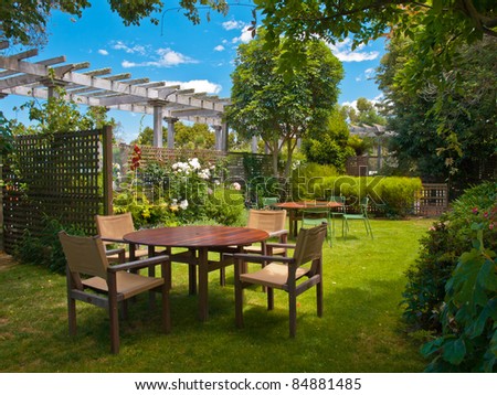 a wooden dining table set in lush garden setting Royalty-Free Stock Photo #84881485